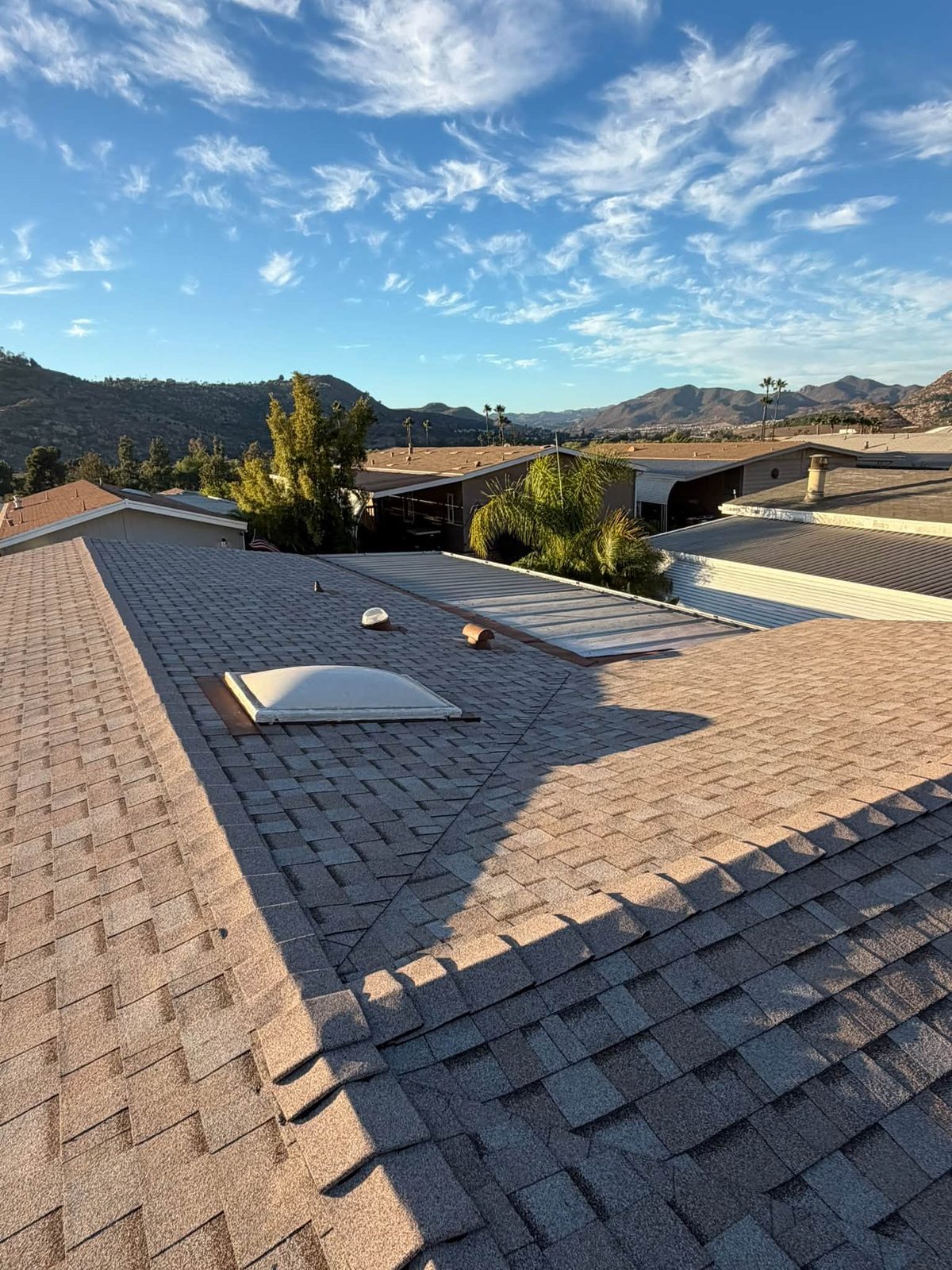 A finished shingle roof by Landeros Roofing under a blue San Diego County sky